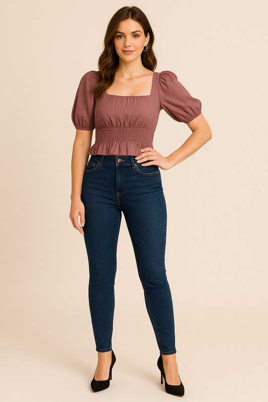 Woman wearing a smocked square neck puff sleeve top in mauve paired with dark blue skinny jeans